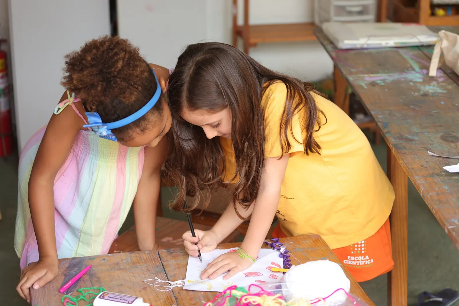 Duas meninas desenham juntas na mesa
